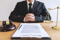 Legal law, advice and justice concept, male lawyer or notary working on a documents and report of the important case and wooden gavel, balance on table in courtroom.