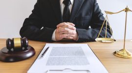 Legal law, advice and justice concept, male lawyer or notary working on a documents and report of the important case and wooden gavel, balance on table in courtroom.