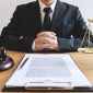 Legal law, advice and justice concept, male lawyer or notary working on a documents and report of the important case and wooden gavel, balance on table in courtroom.
